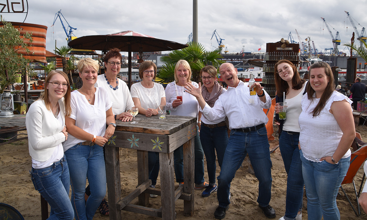 Gruppenfoto gut gelaunter Kollegen bei einem Betriebsausflug in einer Bar im Hafen von Hamburg