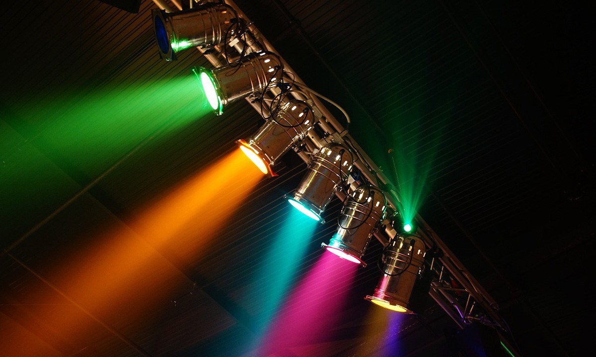 bunte Scheinwerfer an einer Traverse an der Decke einer Eventhalle