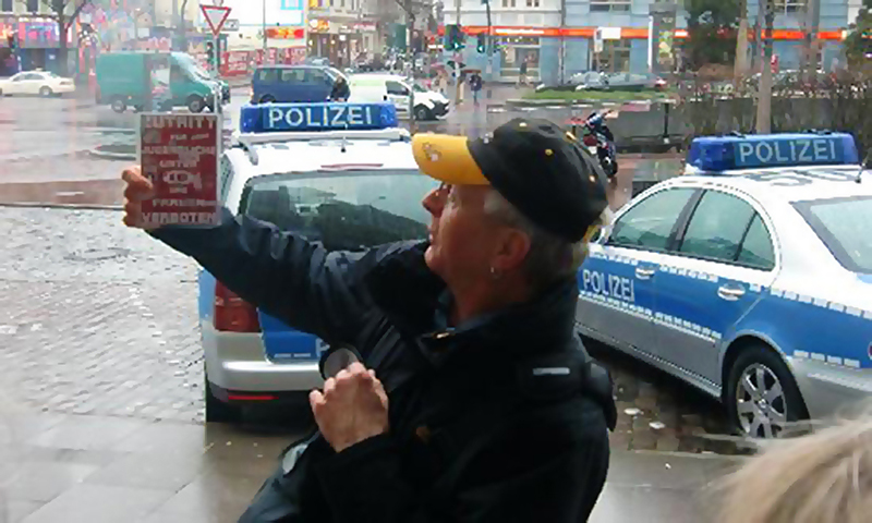 Polizistin vor zwei Streifenwagen bei einer Kriminaltour durch Hamburg