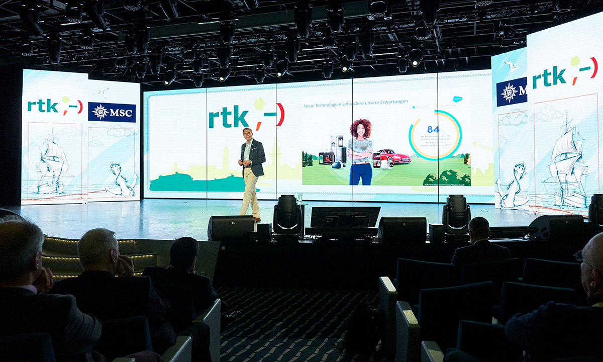 Ein Redner auf der mit grossen Bildschrimen gestalteten Buehne bei der RTK-Tagung
